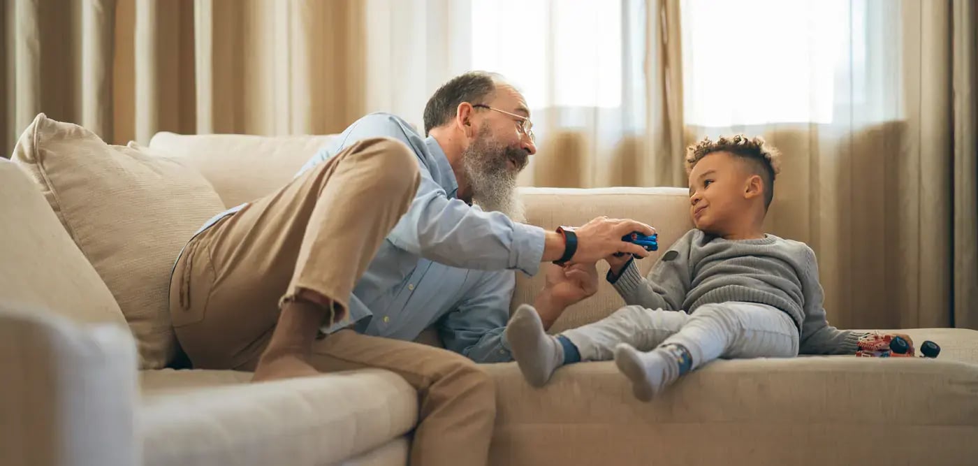 man-playing-with-toy-car-with-grandson