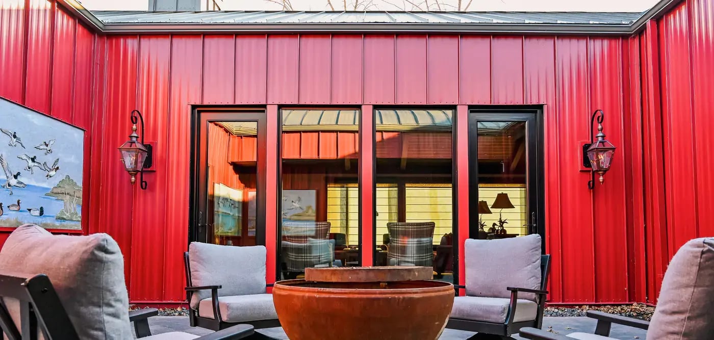 An outside sitting area with firepit in front of a cottage. with red metal siding